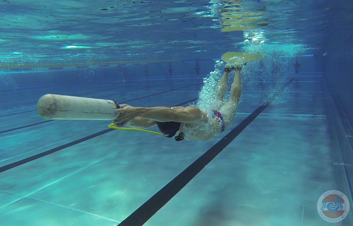 Sporttaucher schwimmt mit Pressluftflasche und Monoflosse im Sportbecken