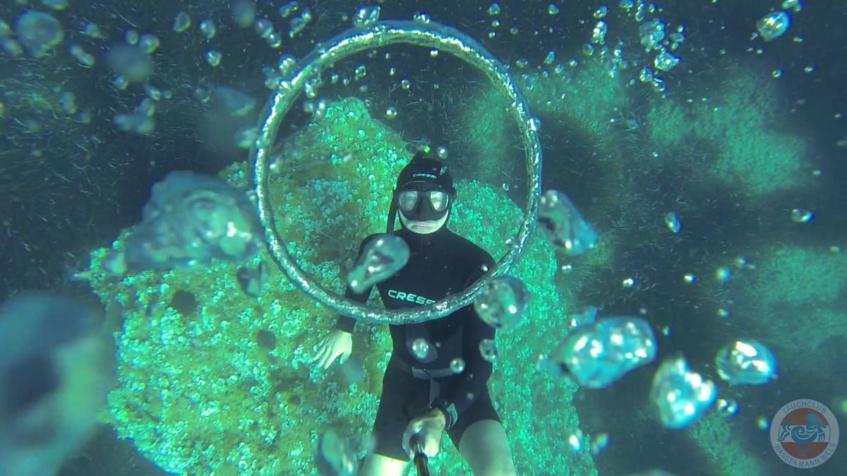 Apnoetaucher blickt unterwasser durch einen Ring aus Luft
